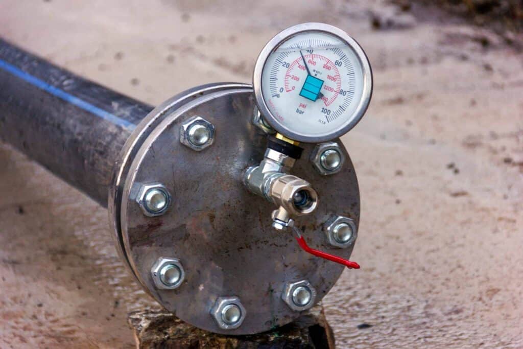 Manômetro acoplado a flange durante teste hidrostático em tubulação industrial
